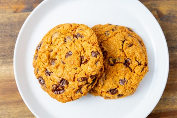 Two chocolate chip cookies on a plate. These cookies are available at Simply Baked Catering in Winchester, Ontario.