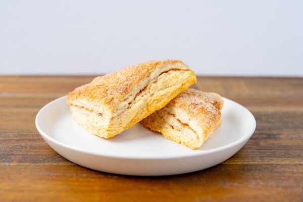 Two cinnamon sugar scones on a plate. These delicious scones are available at Simply Baked Catering Inc. in Winchester, Ontario.