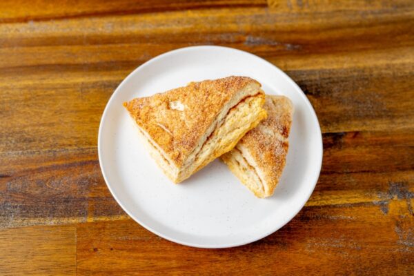 Two cinnamon sugar scones on a plate. These delicious scones are available at Simply Baked Catering Inc. in Winchester, Ontario.