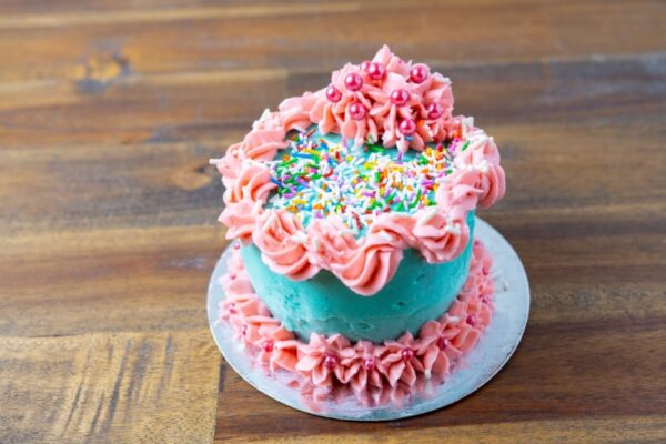 A regular cake with pink and blue icing and sprinkles at Simply Baked Catering Inc. in Winchester, Ontario.