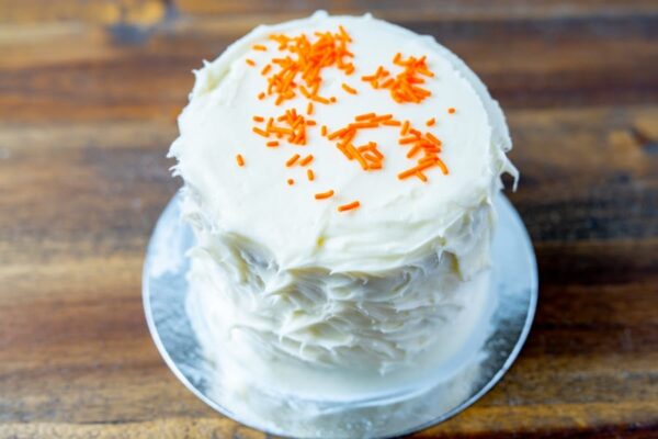 A regular cake with white icing and orange sprinkles at Simply Baked Catering Inc. in Winchester, Ontario.