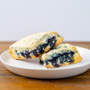 Two blueberry scones on a plate. These delicious scones are available at Simply Baked Catering Inc. in Winchester, Ontario.