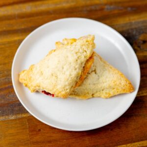Two strawberry and cream scones on a plate. These delicious scones are available during strawberry season at Simply Baked Catering Inc. in Winchester, Ontario.
