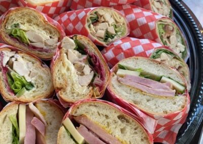 Image of a platter of ham and cheese sandwiches on baguette bread, individually wrapped and ready to serve for a meeting or event. By Simply Baked Catering Inc., Winchester, Ontario.