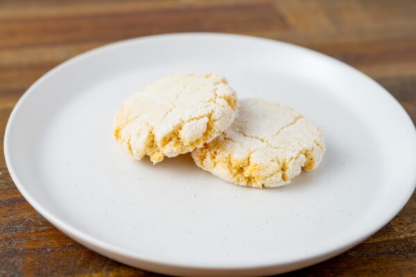 Two Amaretti cookies on a plate. These wheat-free Italian almond cookies are available at Simply Baked Catering Inc. in Winchester, Ontario.