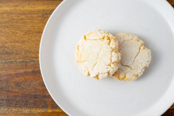 Two Amaretti cookies on a plate. These wheat-free Italian almond cookies are available at Simply Baked Catering Inc. in Winchester, Ontario.